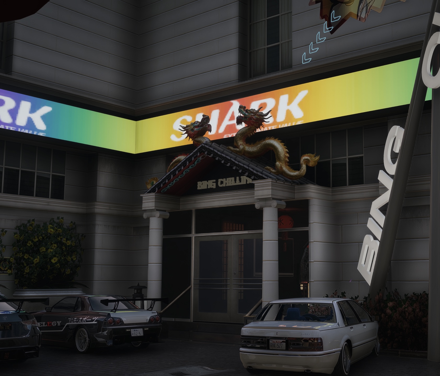Das hell beleuchtete Eingangsportal des „Bing Chilling“ in der Dämmerung, davor geparkte Fahrzeuge – ein Geschäft in Narco City.